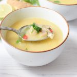 Taking a spoonful of soup from a low FODMAP tom kha kai soup