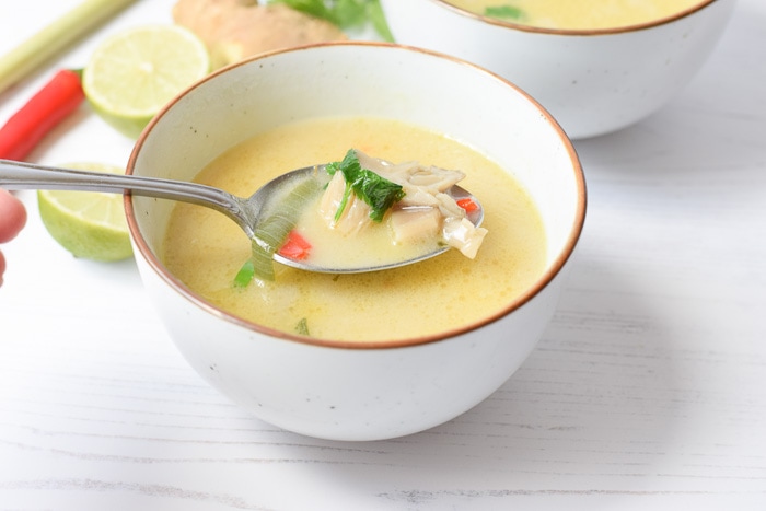Taking a spoonful of soup from a low FODMAP tom kha kai soup