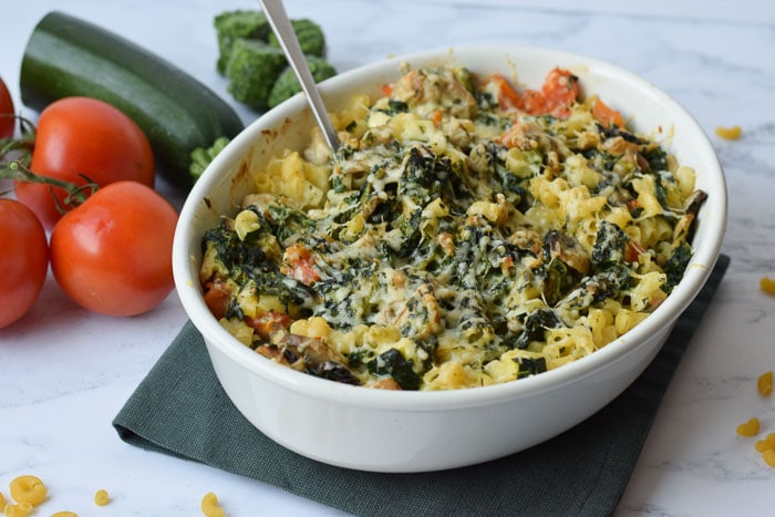 low FODMAP macaroni casserole with tomatoes, spinach and zucchini in the background
