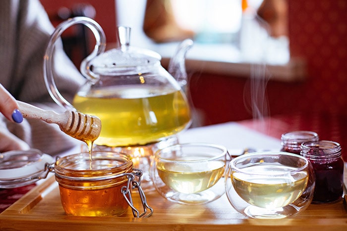 Een dienblad met thee, theekopjes en honing