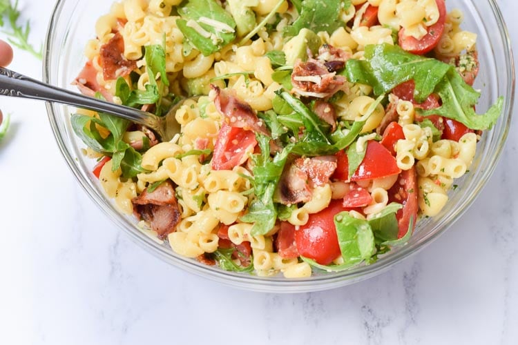 A low FODMAP BLT pasta salad in a glass bowl with a spoon in it