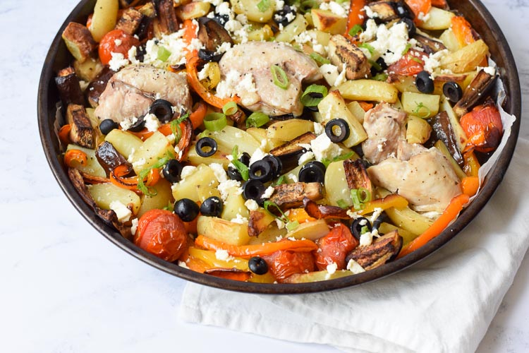 Een bakplaat met kip, groenten, aardappelen, feta en olijven