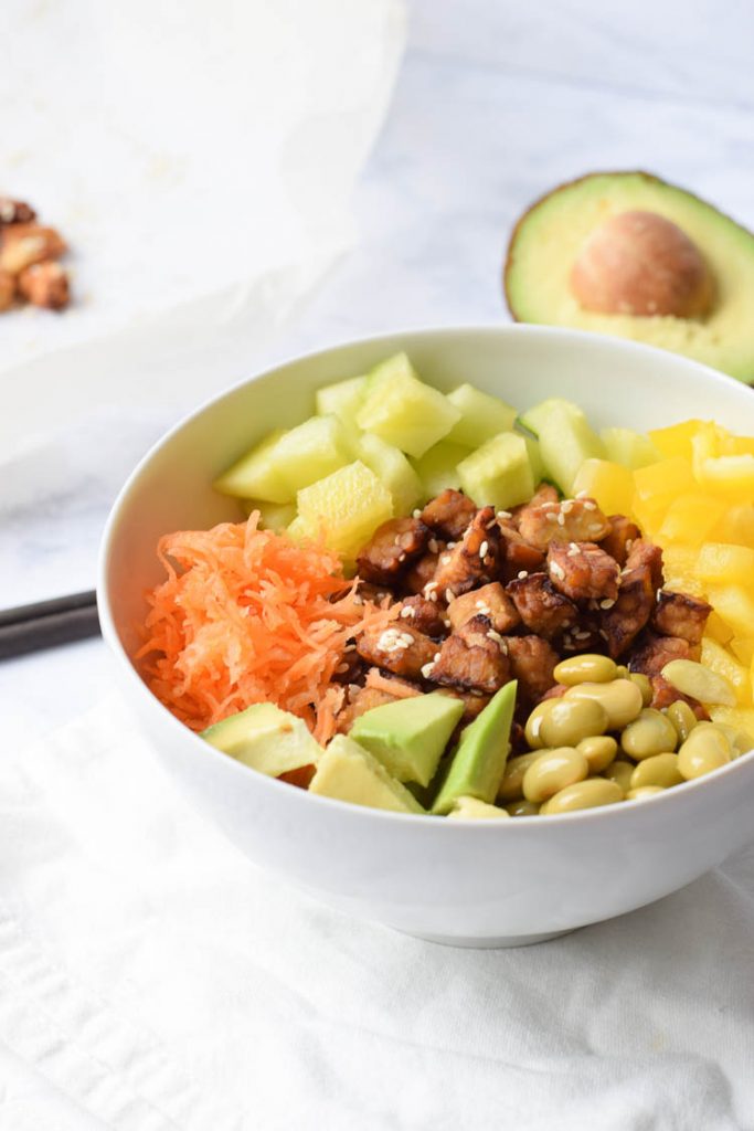 Low FODMAP vegan poke bowl in a bowl with an avocado next to it
