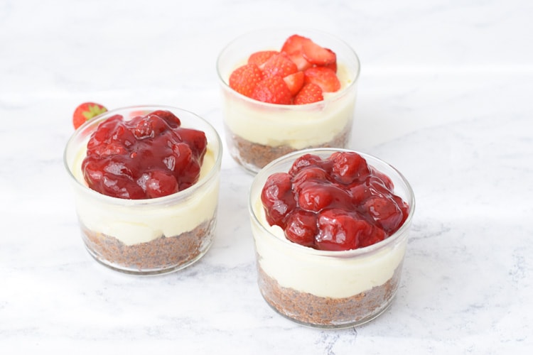Three low FODMAP mini strawberry cheesecakes in a glass
