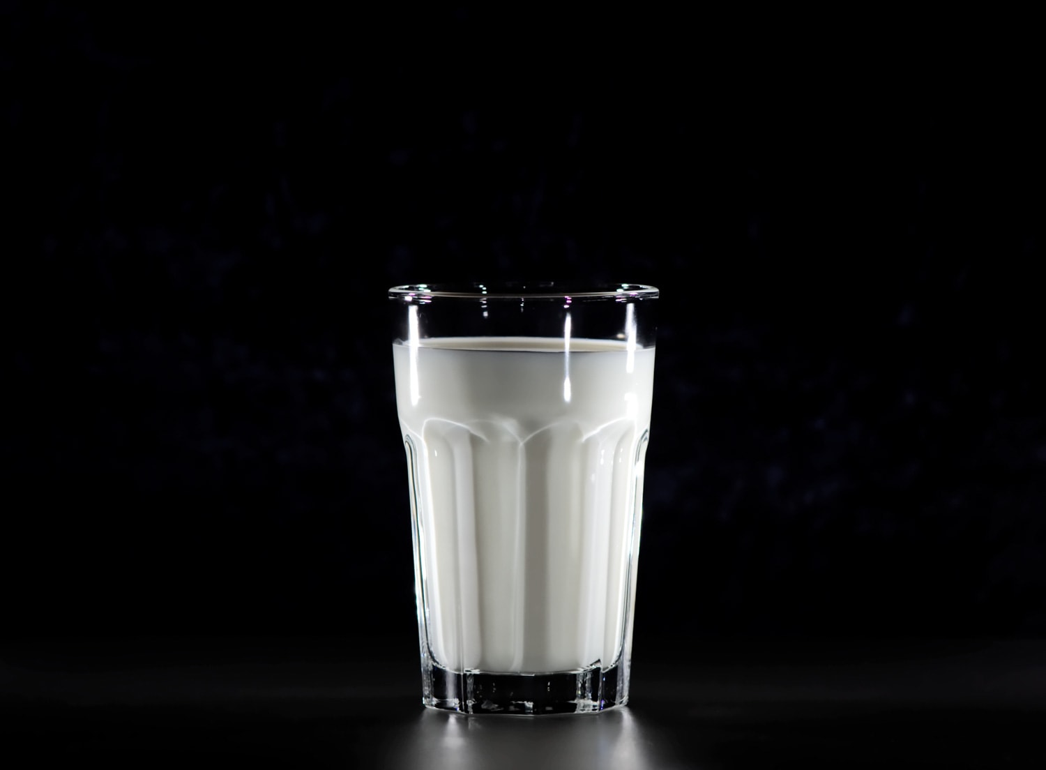 Een glas melk met een zwarte achtergrond