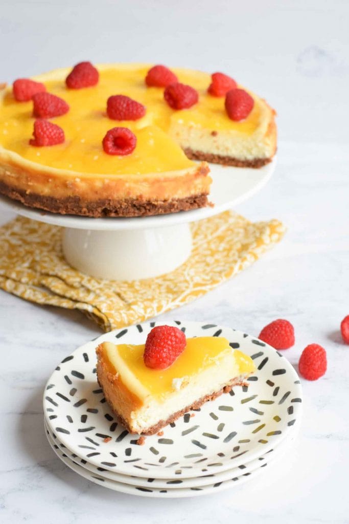 Gluten-free lemon curd cheesecake on a serving platter with a piece on a plate