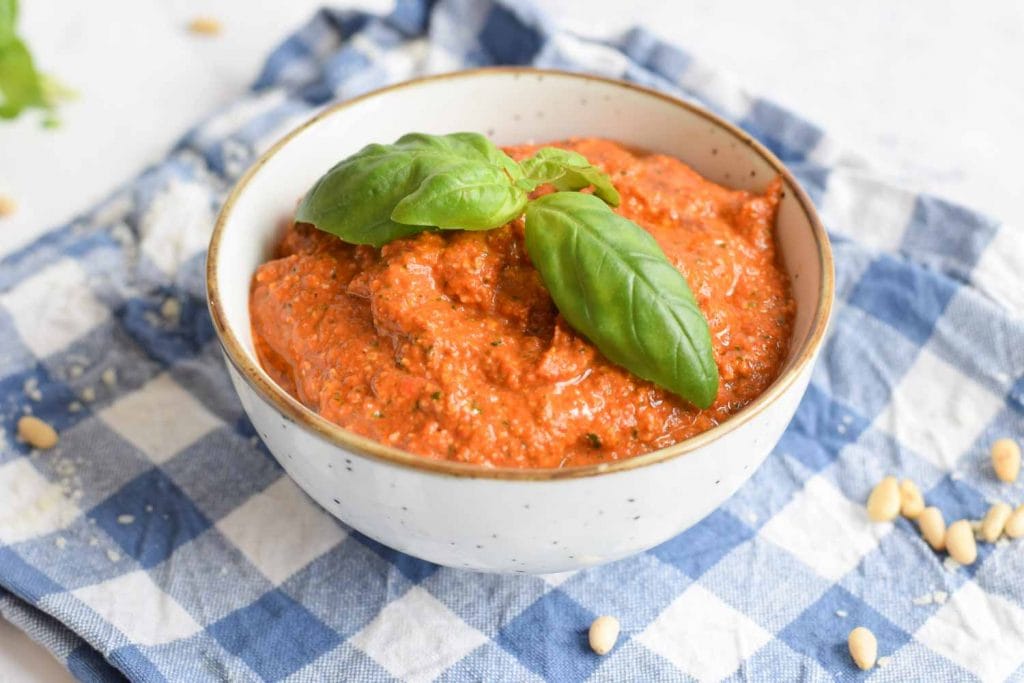 Low FODMAP red pesto in a bowl with basil on top