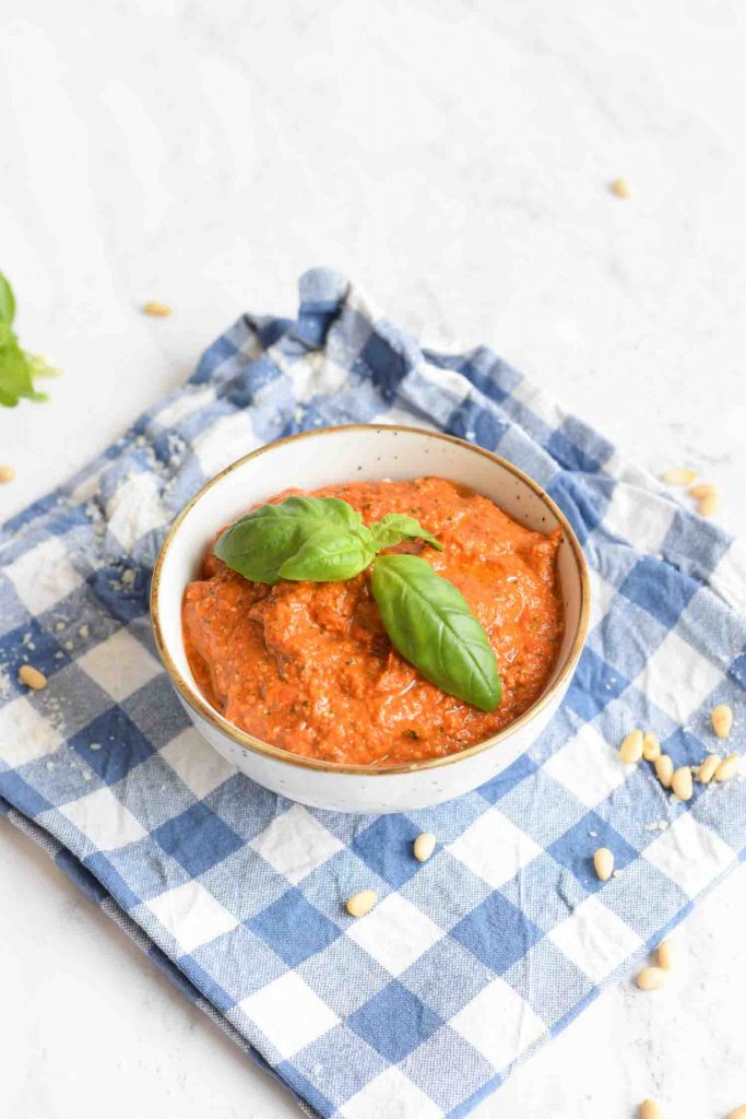 Low FODMAP red pesto in a bowl with pine nuts on the side
