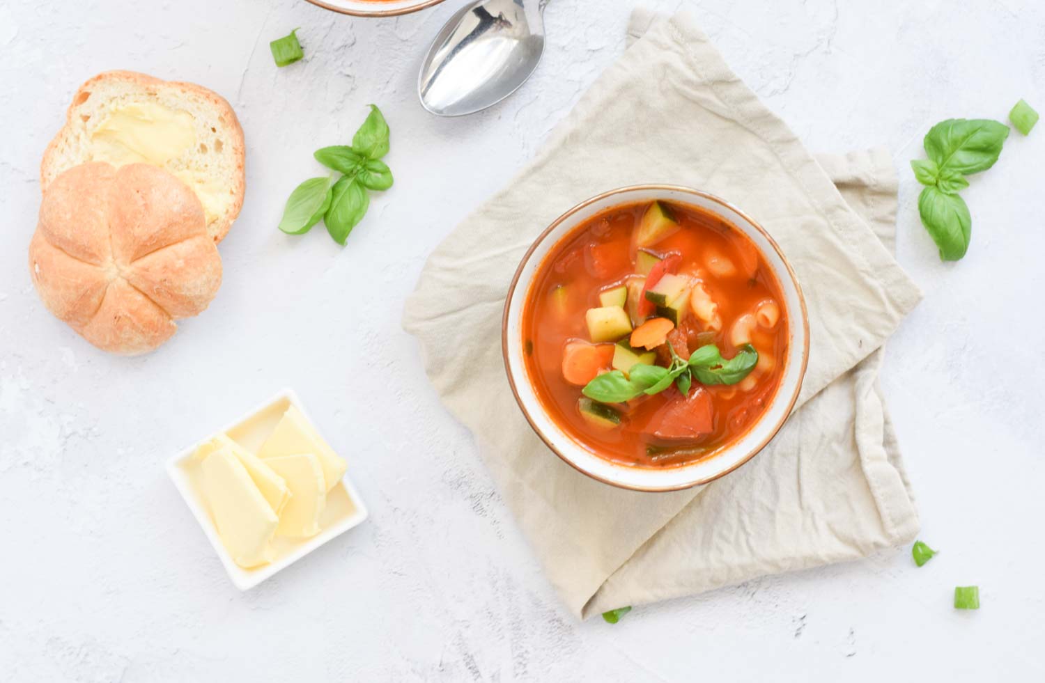 A low FODMAP minestrone soup with a some butter and a bread on the side
