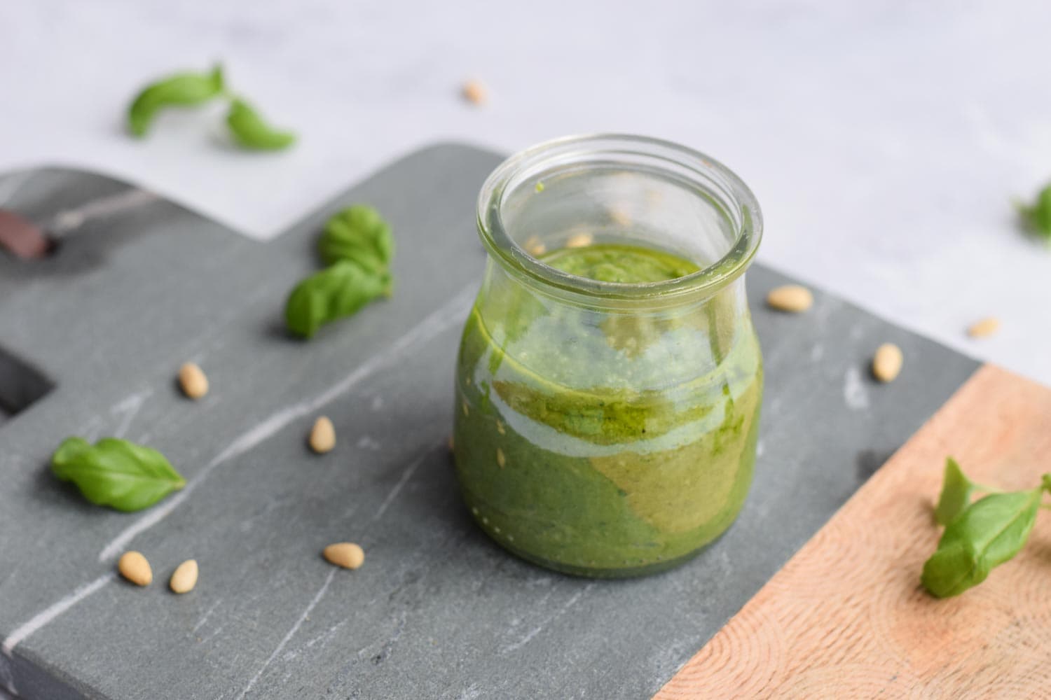 Low FODMAP pesto in a jar with pine nuts around