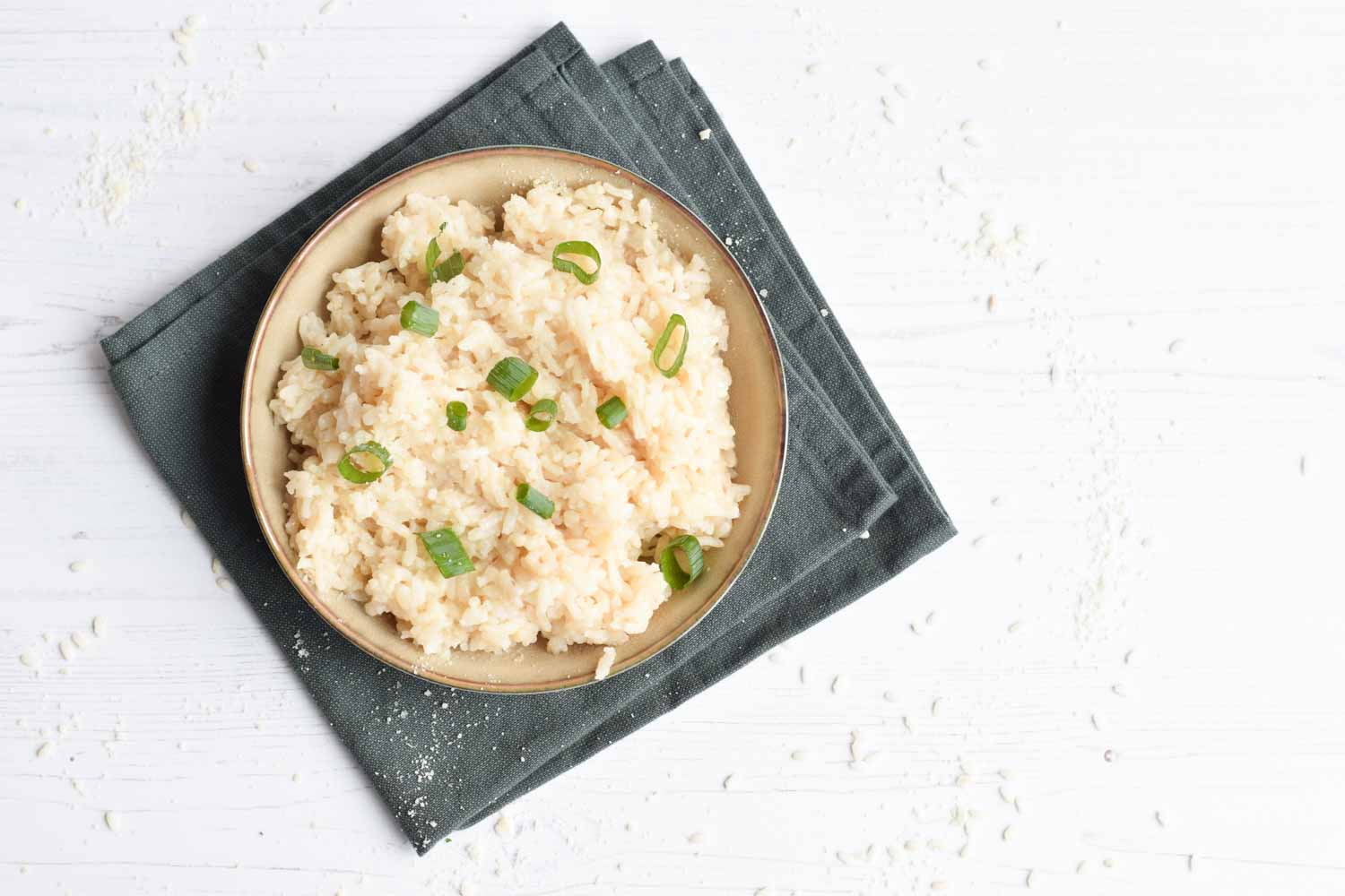 A basic recipe of risotto in a bowl with spring onion on top