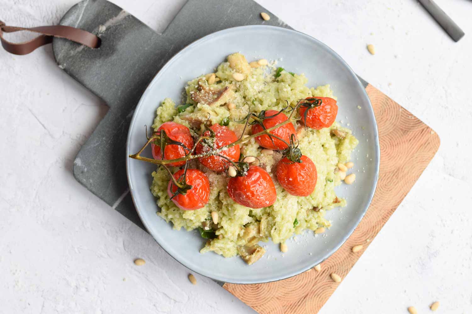 A plate with risotto with pesto and tomatoes on a cutting board