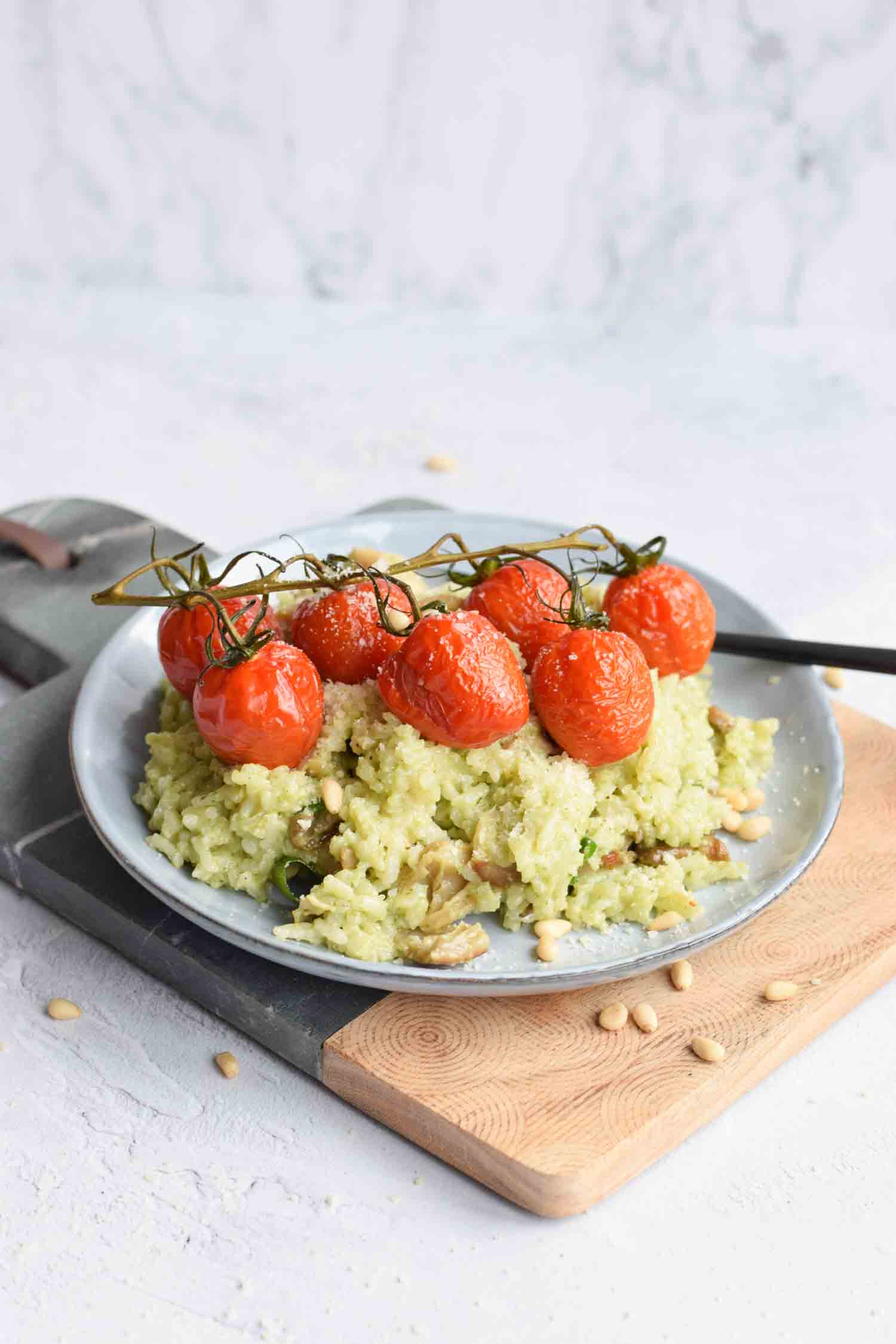Een bord met risotto met groene pesto en tomaatjes