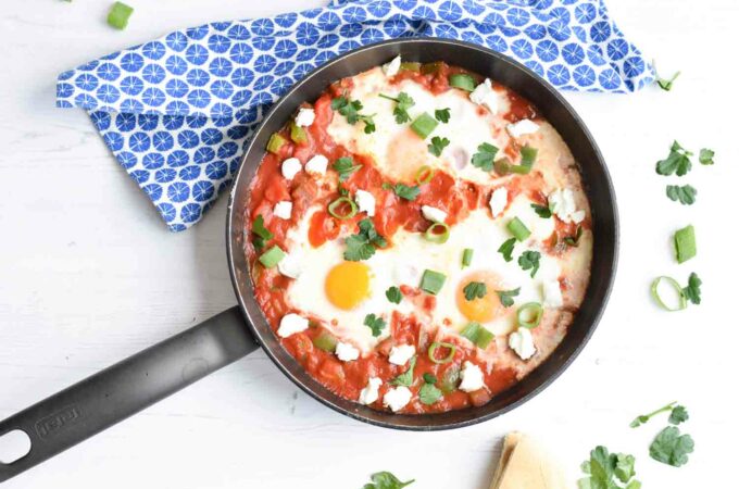 Low FODMAP shakshuka in a pan with spring onion and parsley