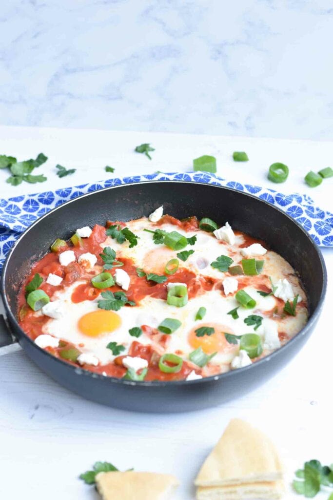 A pan with low FODMAP shakshuka with pieces of pita next to it