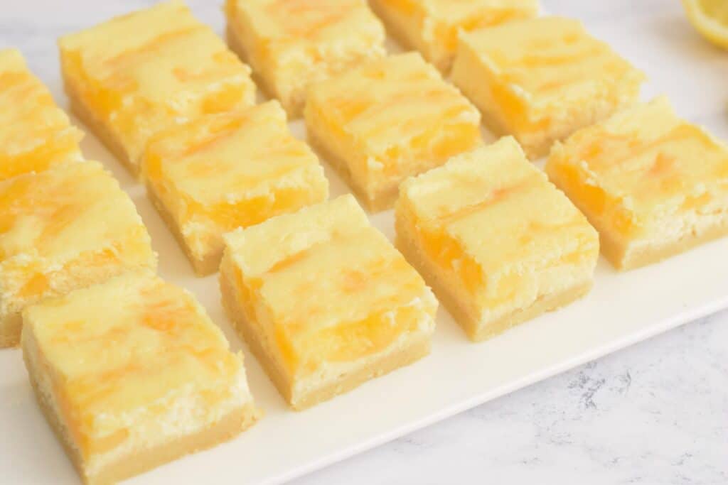 Twaalf glutenvrije lemon cheesecake bars op een bord