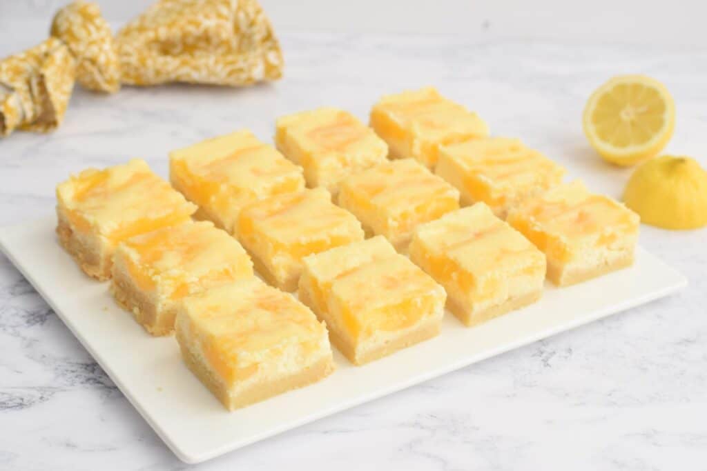 Een bord met lactose-arme lemon cheesecake bars en een citroen ernaast