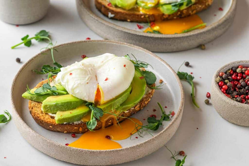 Een bord met toast met avocado en een gepocheerd ei