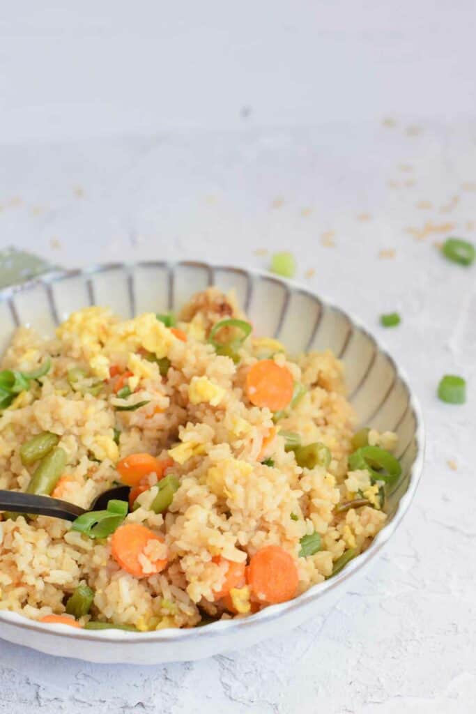 A bowl of fried rice with a spoon into it