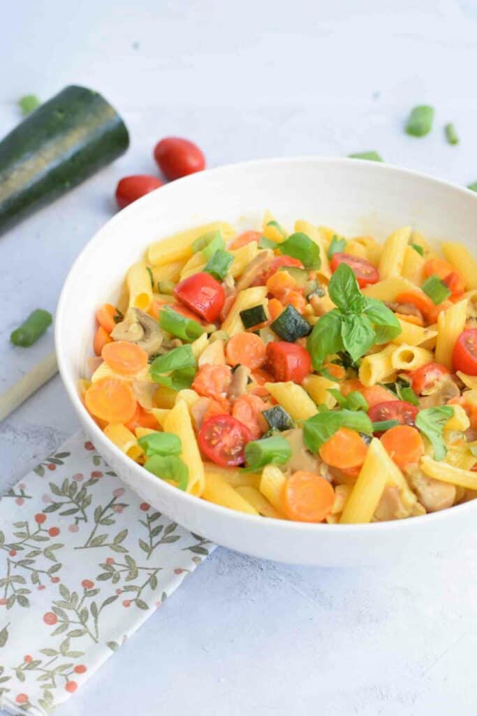 A bowl of low FODMAP pasta primavera photographed from the side