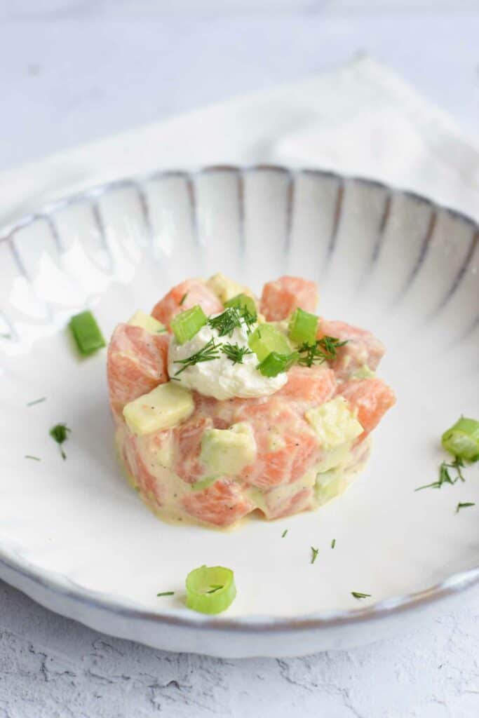 A low FODMAP salmon tartare with avocado topped with creme fraiche, dill and spring onion