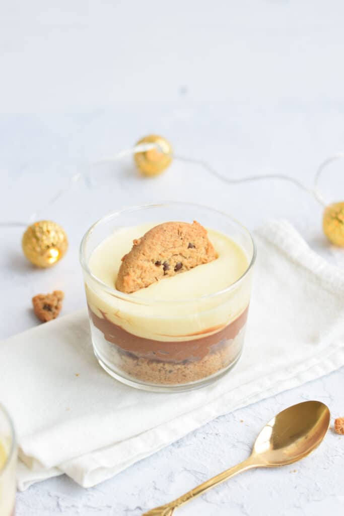 A glass of low FODMAP chocolate mousse with a white and a dark layer, with a cookie in the top