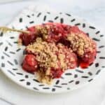 A plate with low FODMAP strawberry raspberry crisp with a golden spoon