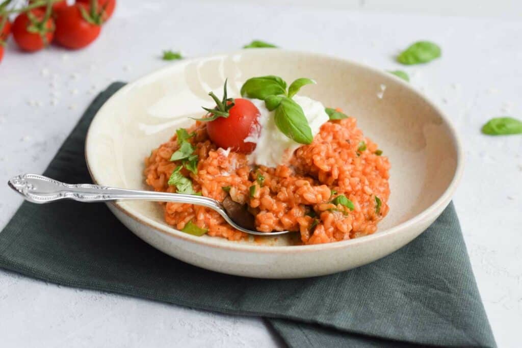 A plate with low FODMAP tomato risotto with burrata and fresh basil