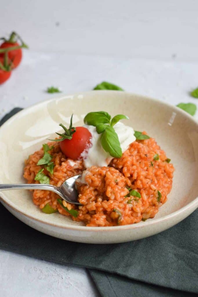 A plate of low FODMAP tomato risotto with a spoon in it