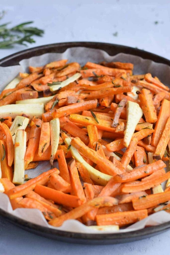 A baking sheet with oven baked carrots, parsnip and sweet potato