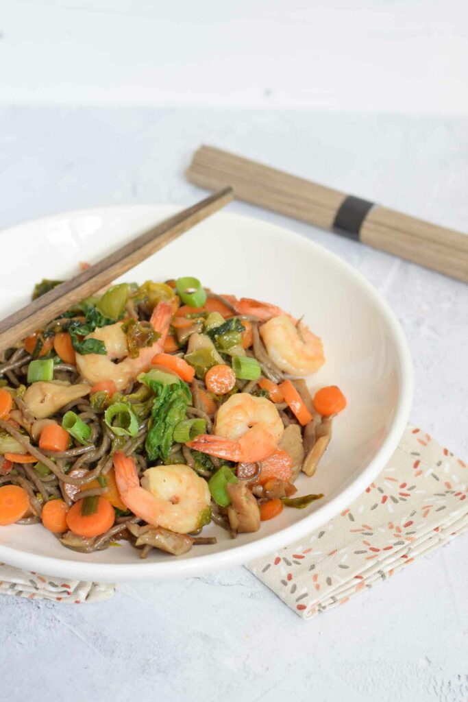 Low FODMAP shrimp lo mein noodles in a deep plate with chopsticks
