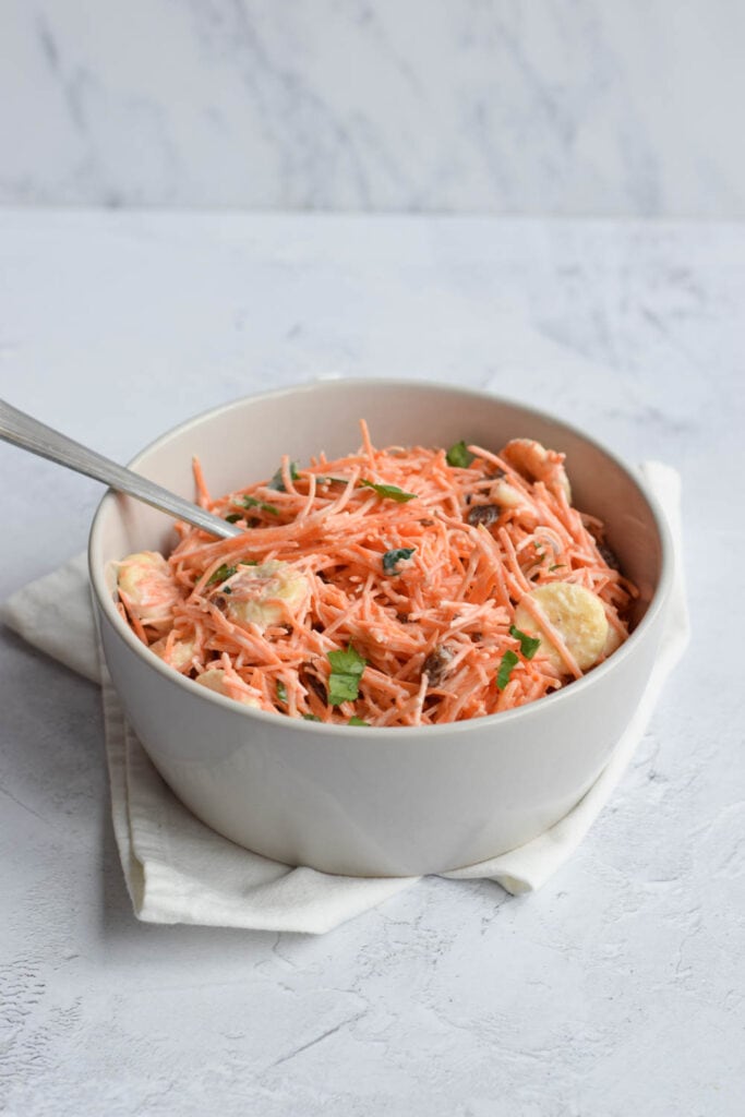 A low FODMAP carrot salad in a bowl with a spoon in it