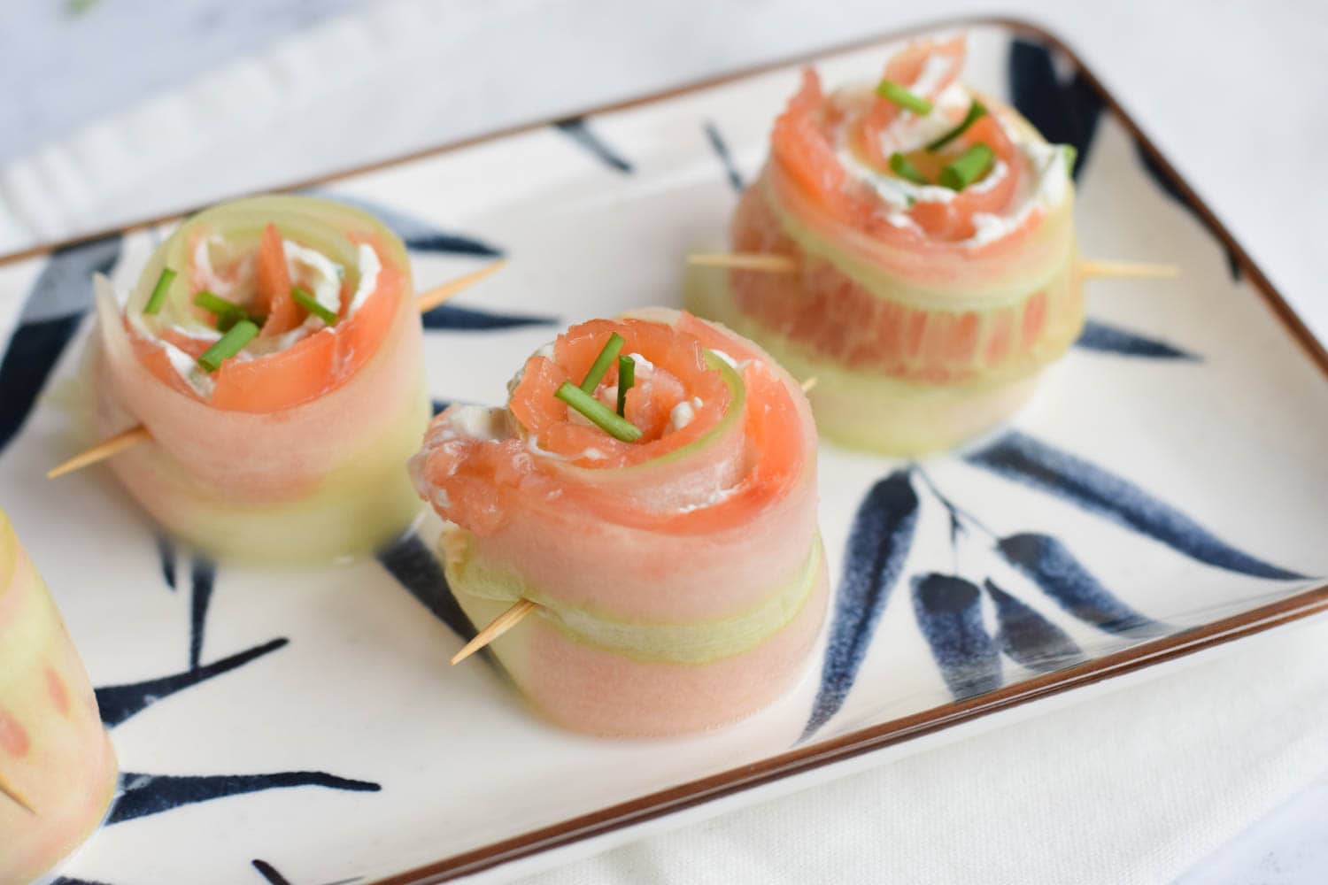 Low FODMAP smoked salmon and cucumber rolls with cream cheese and dill held together by a toothpick
