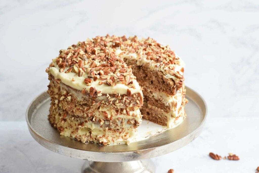 A gluten-free hummingbird cake with a piece cut out of it