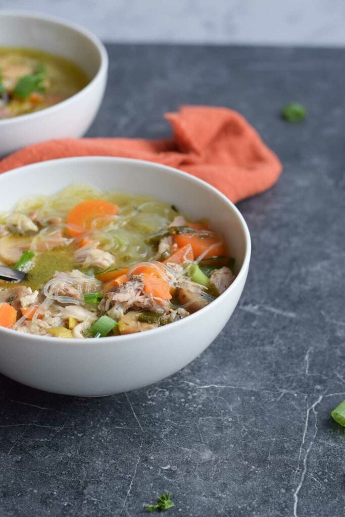 Low FODMAP chicken soup in a bowl with an orange napkin next to it