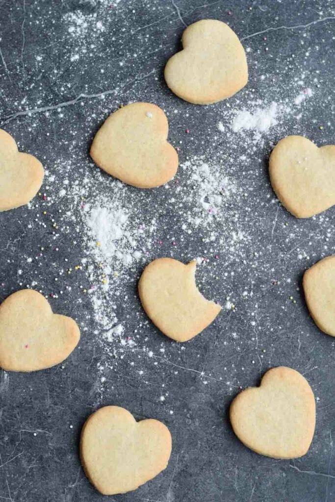 Gluten-free sugar cookies laying on a dark background with flour spread in between