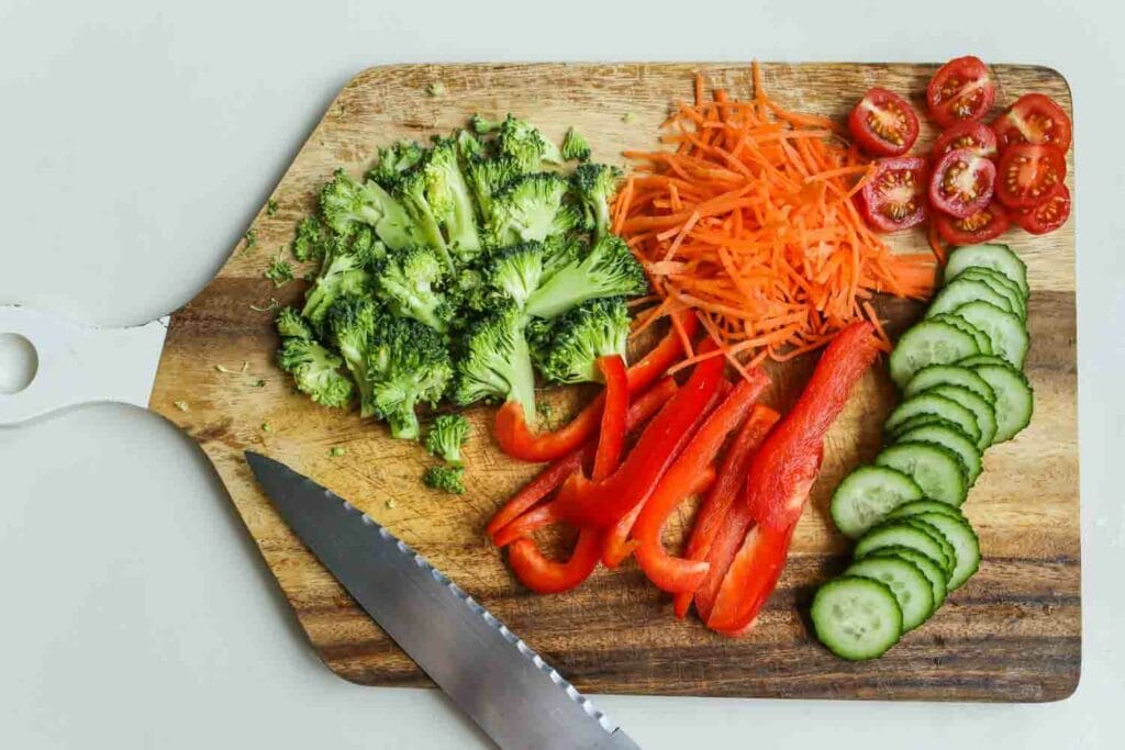 A cutting board with different kinds of veggies and a knife