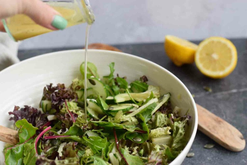 Low FODMAP green salad where a dressing is being poured on