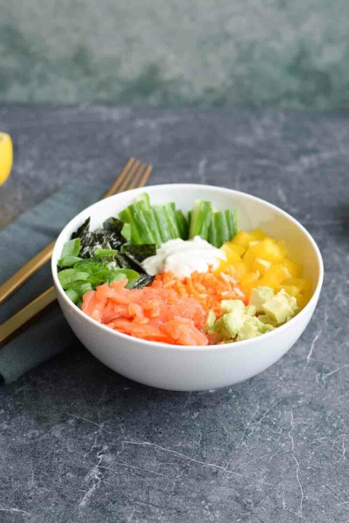A colorful low carb poké bowl with smoked salmon, vegetables and carrot rice