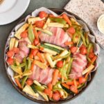 A low FODMAP traybake with chicken in bacon and vegetables photographed from above
