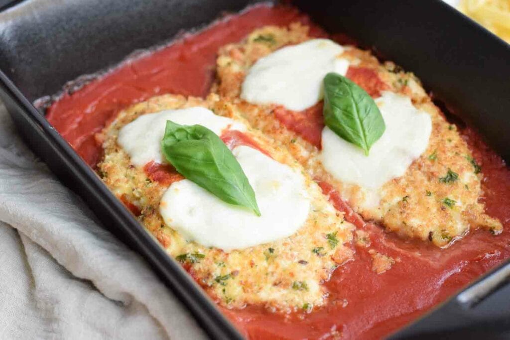 Low FODMAP chicken parmesan with tomato sauce in a dish