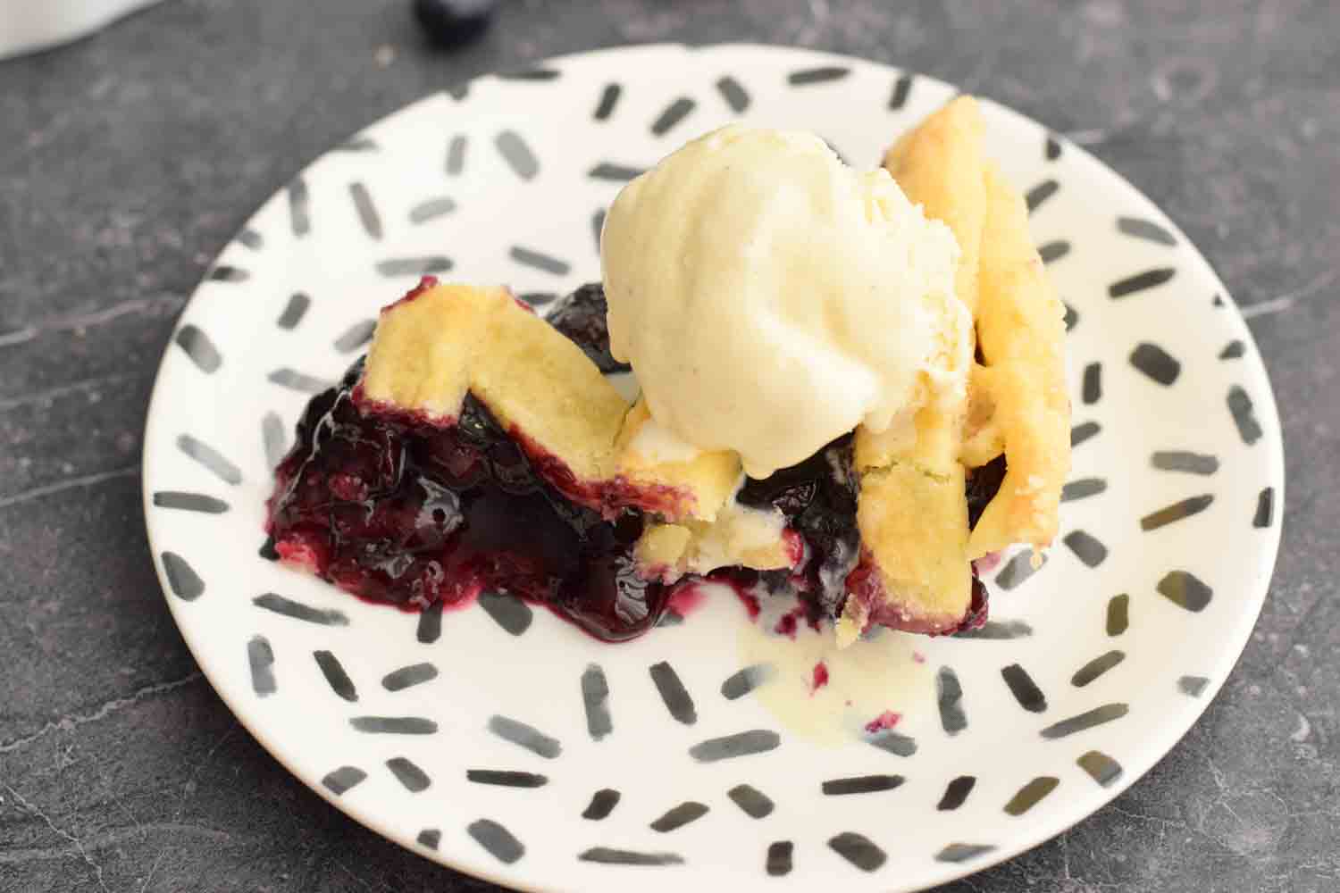 A piece of blueberry pie with ice cream on top