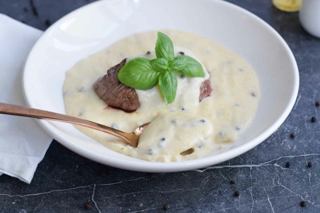 A plate with steak and creamy low FODMAP peppercorn sauce