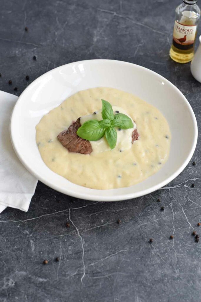 Steak with low FODMAP peppercorn sauce on a white plate