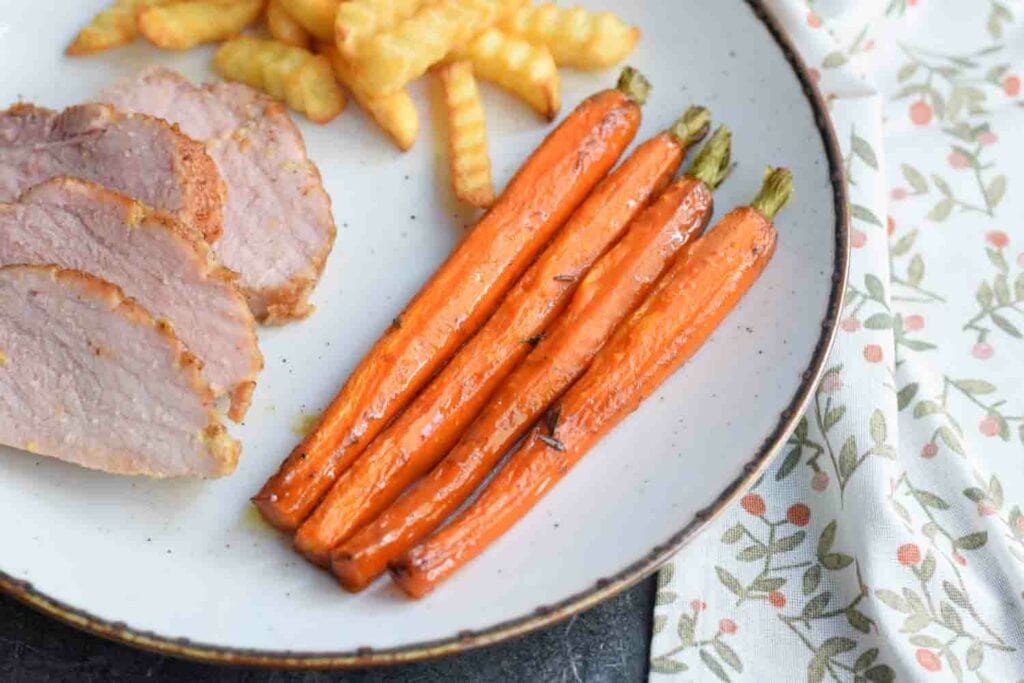 Low FODMAP glazed carrots on a plate next to ham and fries