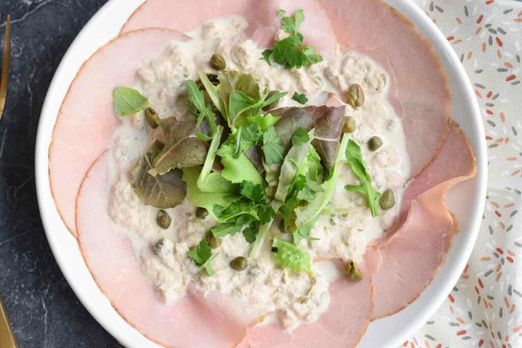 A plate of low FODMAP vitello tonnato with lettuce on top