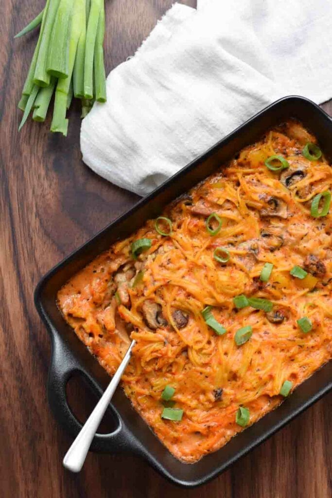 Low FODMAP chicken spaghetti in a casserole dish with spring onion next to it