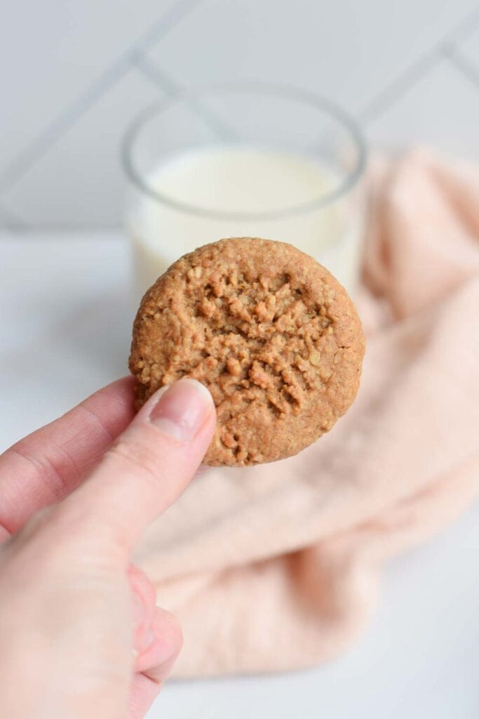 A low FODMAP peanut butter cookie with a glass milk next to it